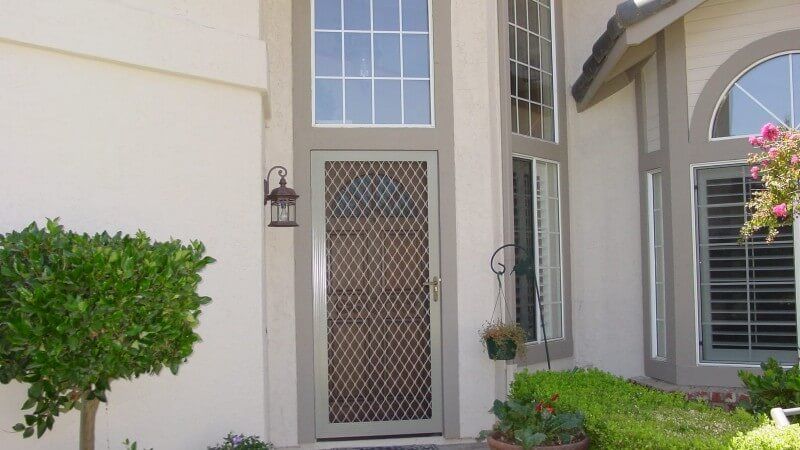 White Lattice style security screen door at the front of a house.